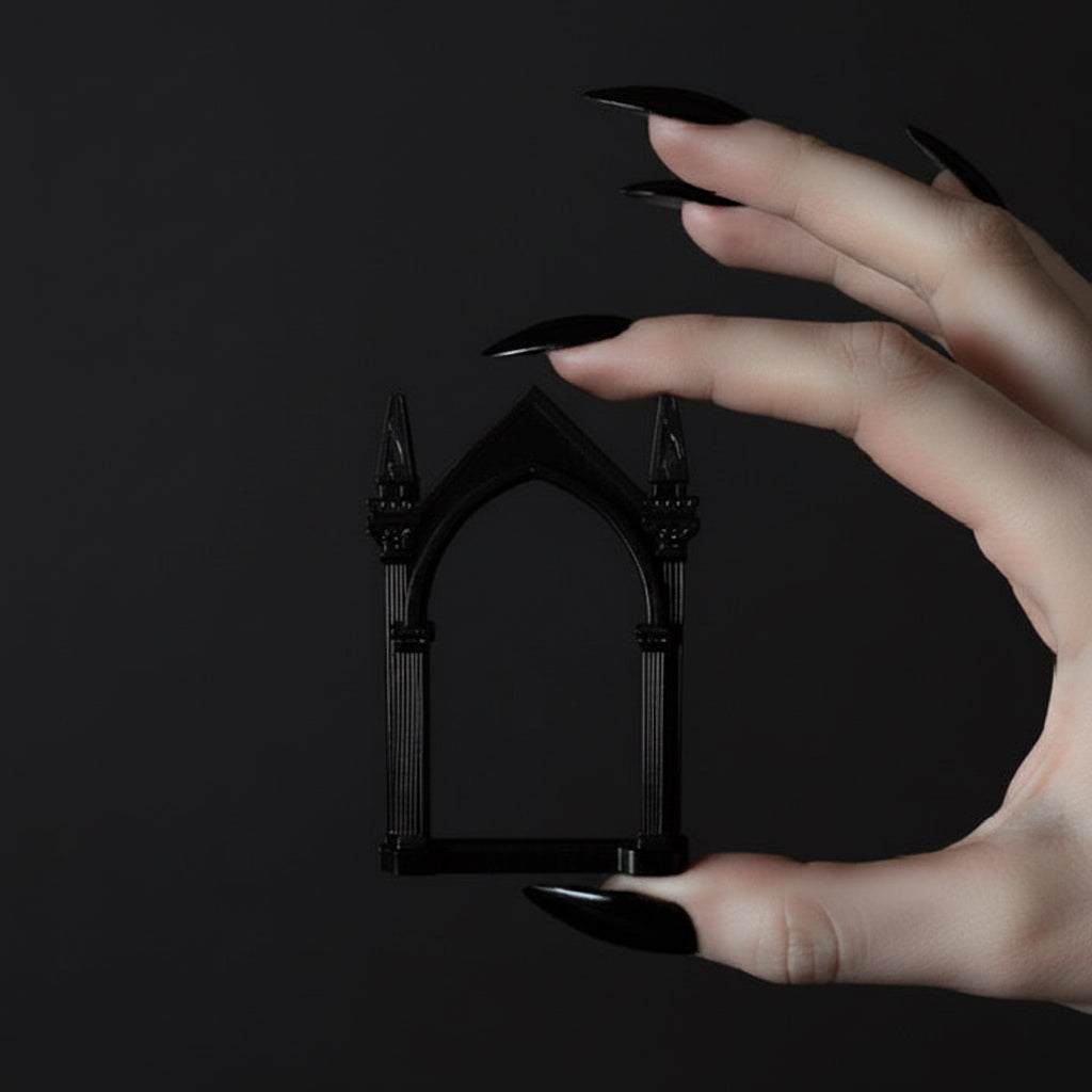 Hand holding a small black arch-shaped picture frame against a dark background