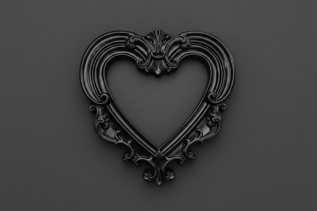 A black ornate heart-shaped decorative frame or picture frame with baroque-style scrollwork, centered on a dark gray background.