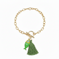 Gold bracelet with a green fish and green tassel on a white background.