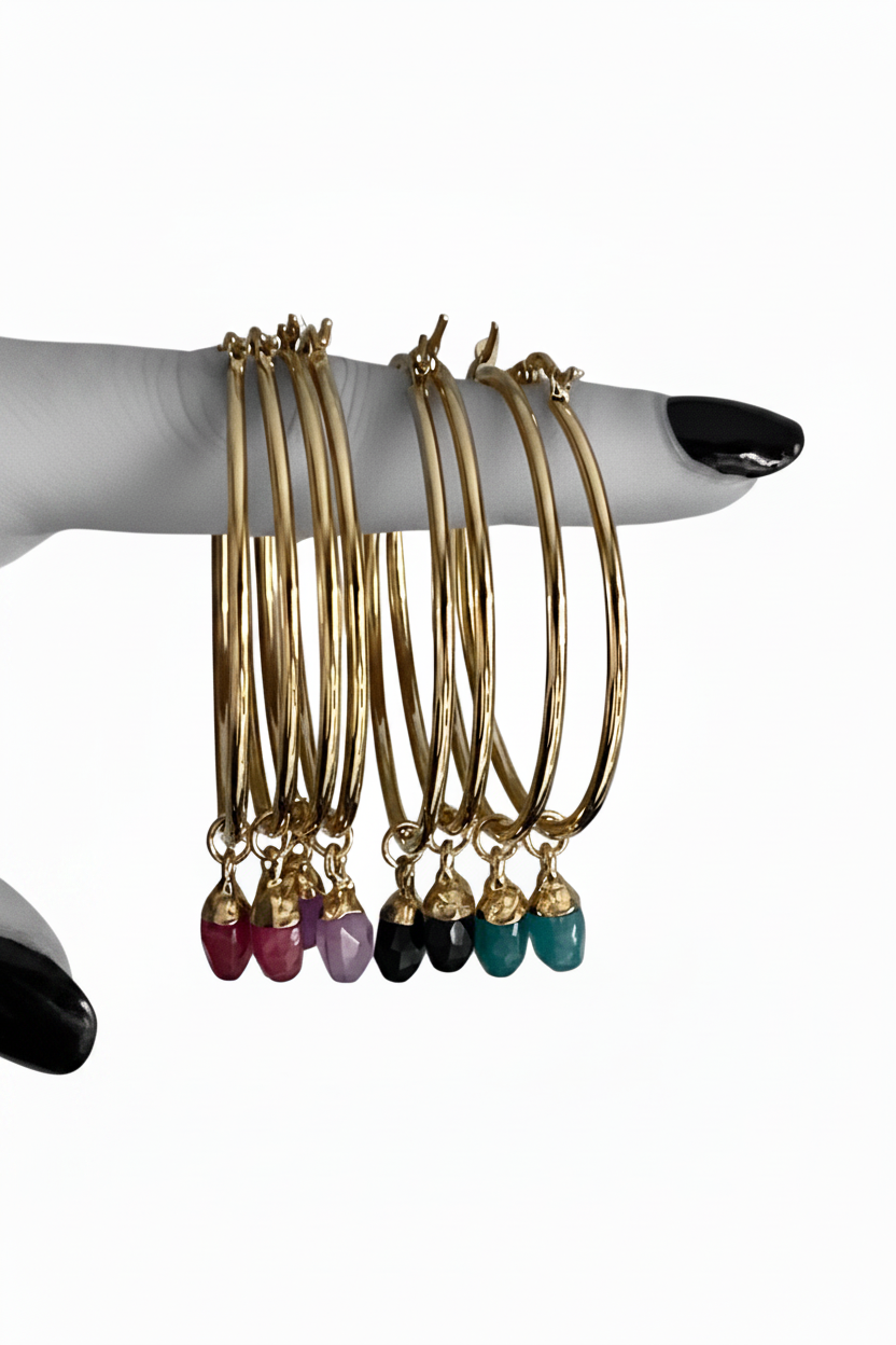 Set of gold hoop earrings with colourful crystals on a white background