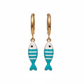 Gold hoop earrings with fish-shaped charms on a hand