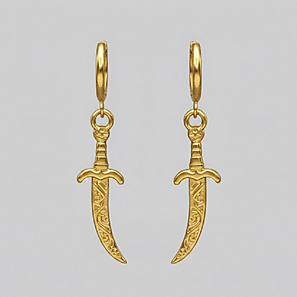 Gold dagger-shaped earrings on a light gray background