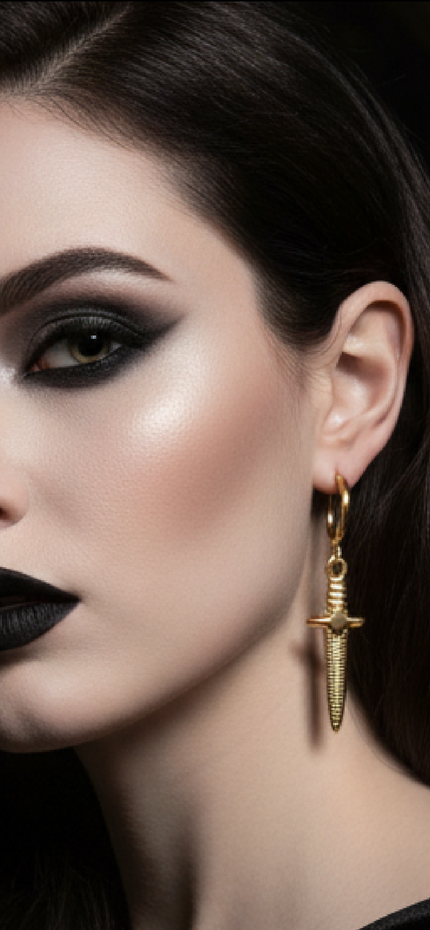 Close-up of a woman wearing gold dagger earrings with a dark background