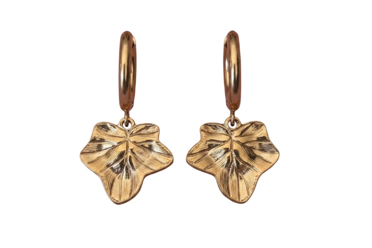 A pair of gold hoop earrings featuring textured ivy leaf charms shown against a plain white background.