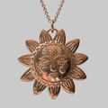 Gold sun-shaped pendant necklace on a light grey  background