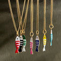 Gold necklaces with colorful fish pendants on a dark background