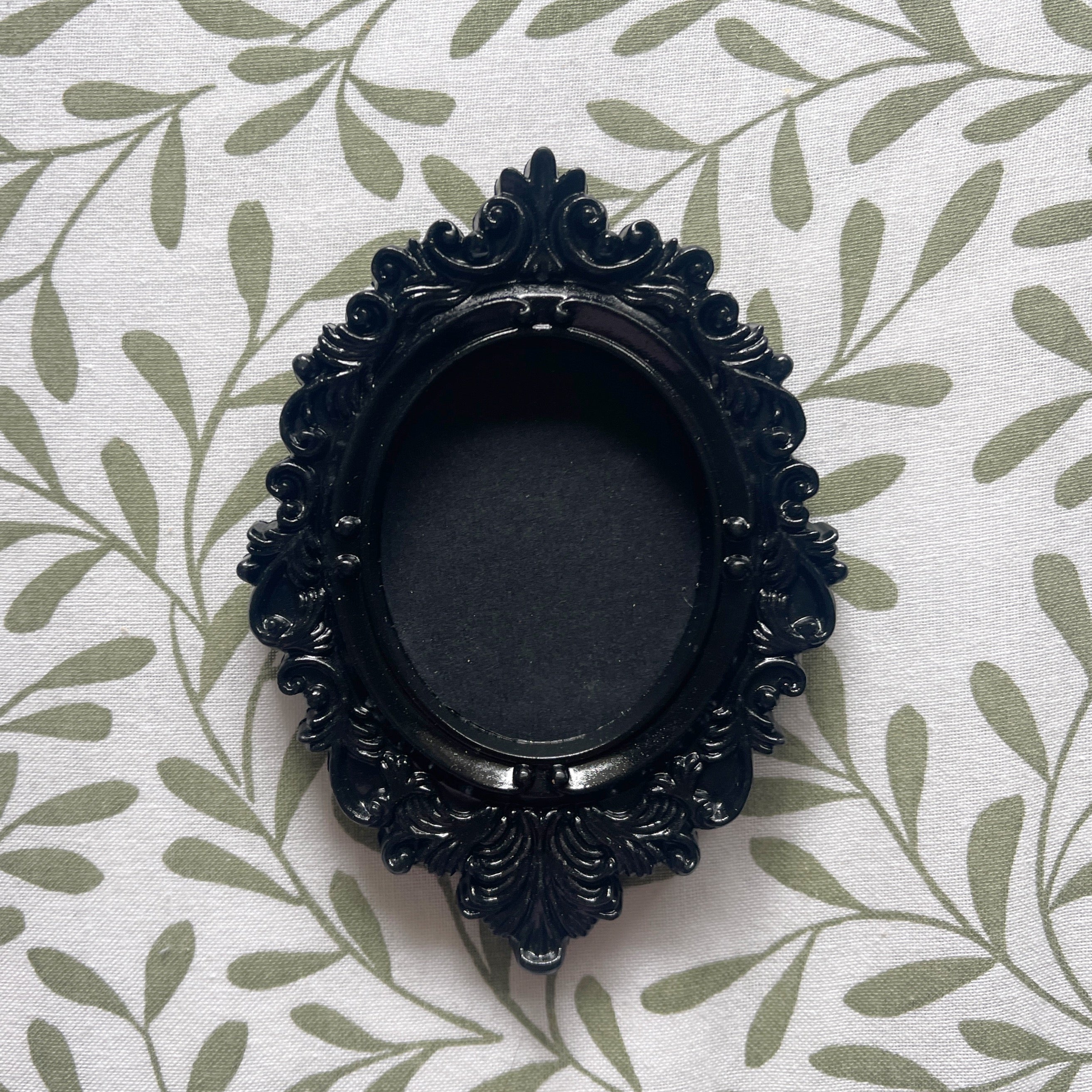 Decorative black frame on a white fabric background with green leaf pattern