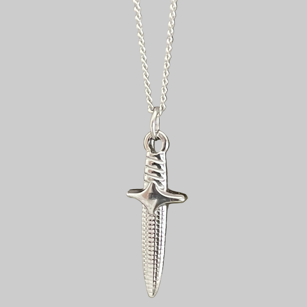 Silver dagger pendant on a chain against a gray background