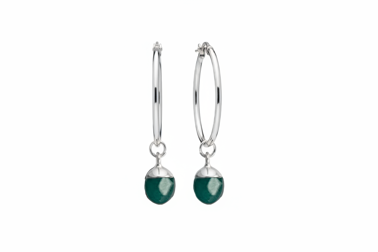 A pair of silver hoop earrings with a turquoise oval crystal against a white background 