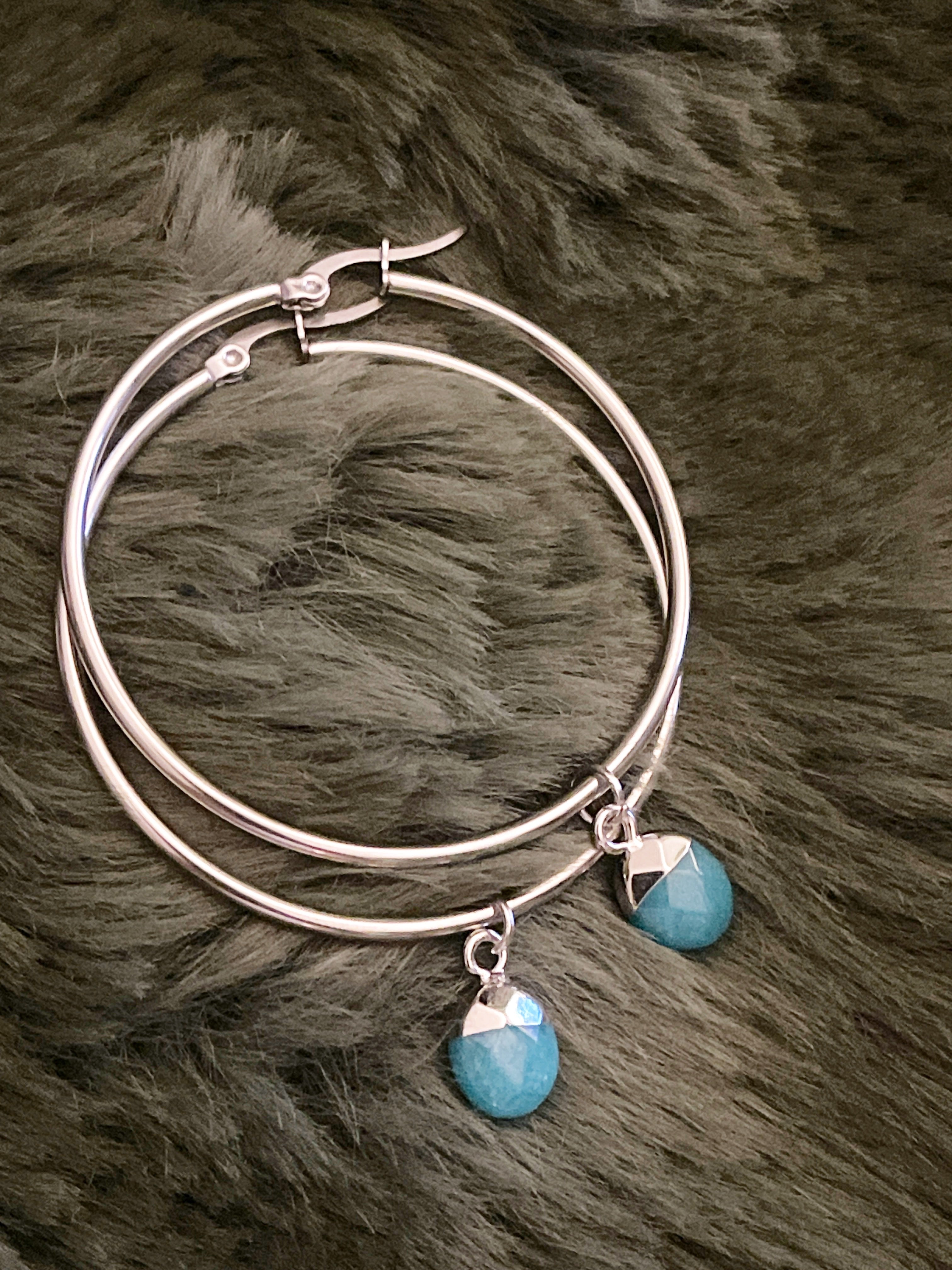 Silver hoop earrings with turquoise crystals on a fur surface