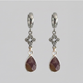 Pair of silver earrings with teardrop-shaped gemstones on a gray background