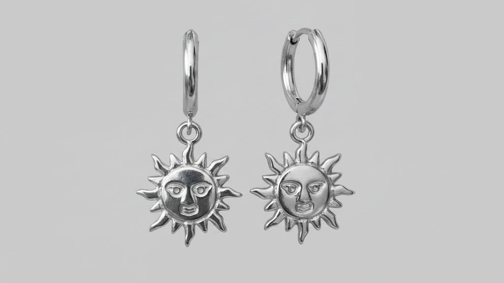 Silver sun-shaped earrings with face design on a gray background