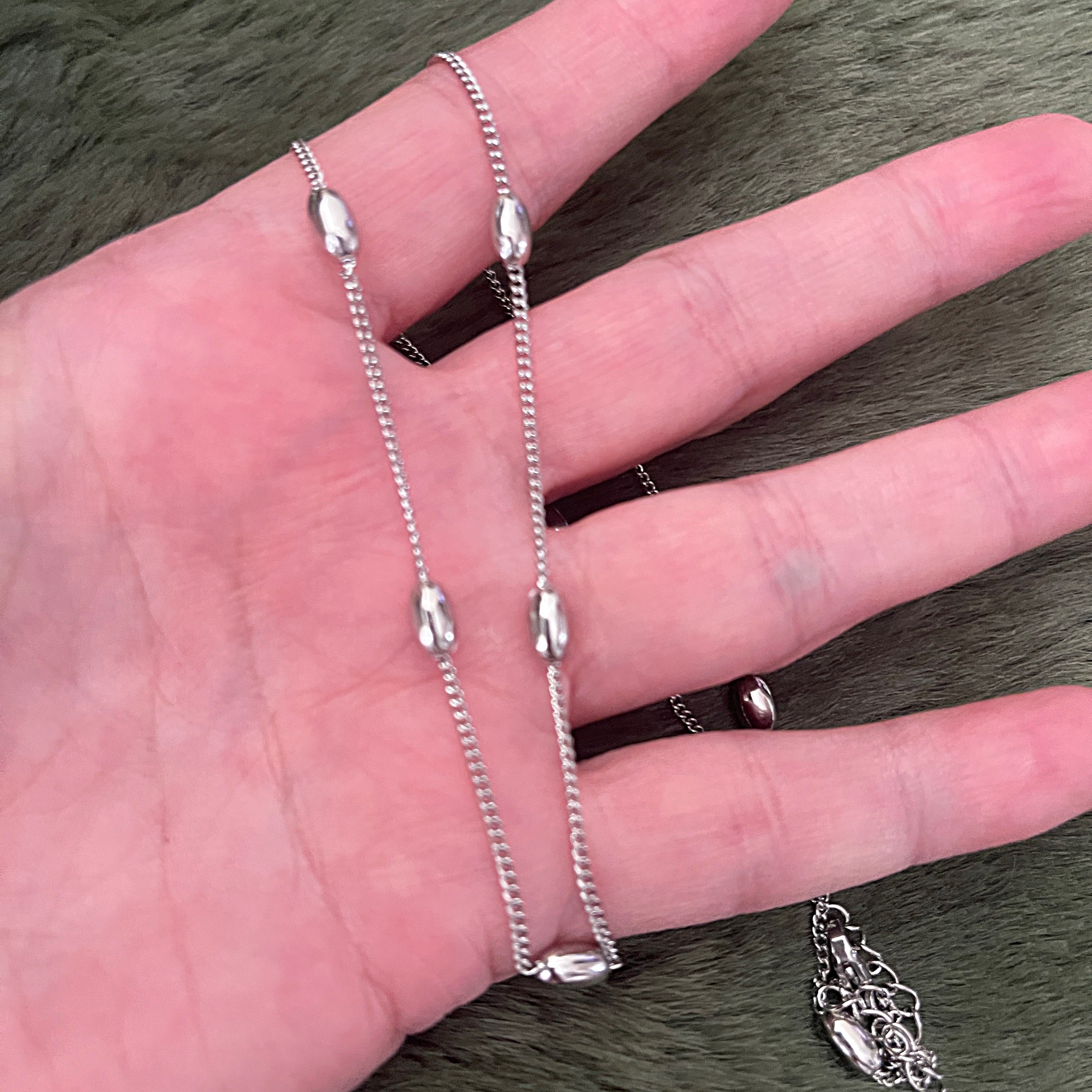 Silver chain on a hand with a neutral background