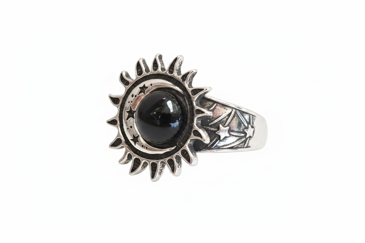 A silver ring featuring a sunburst and moon design with a central black round stone and star details on the band, shown against a plain white background.